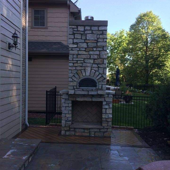 A stone fireplace with a pizza oven in the backyard of a house