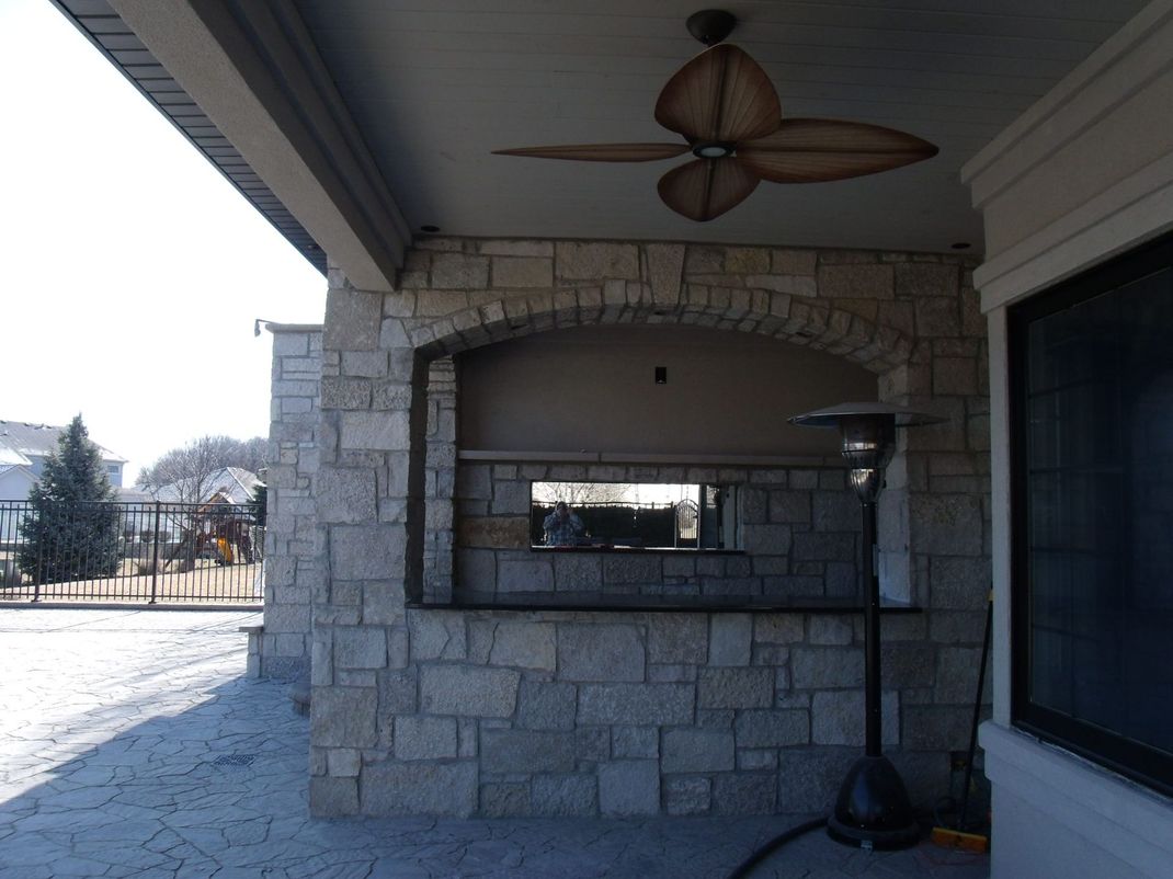 A stone wall with a ceiling fan above it
