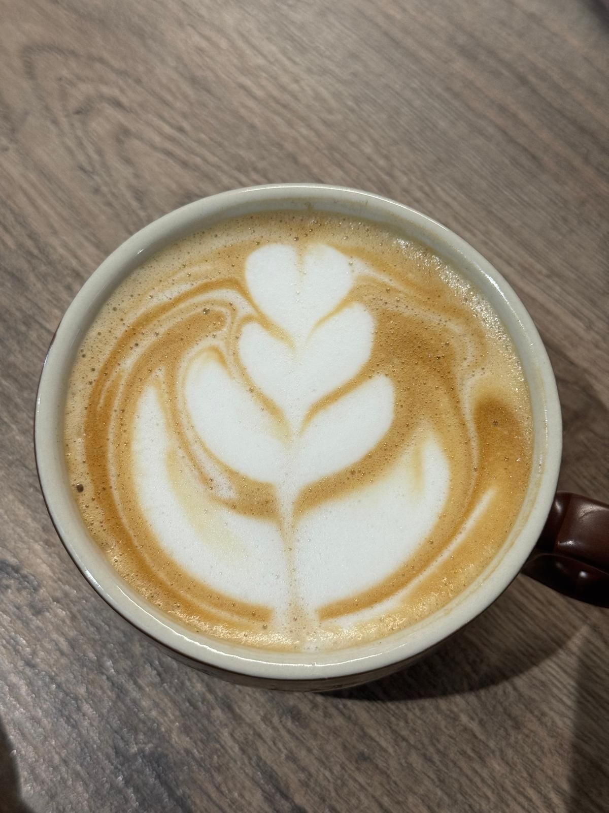 Una tazza di cappuccino con un disegno di foglia sulla schiuma