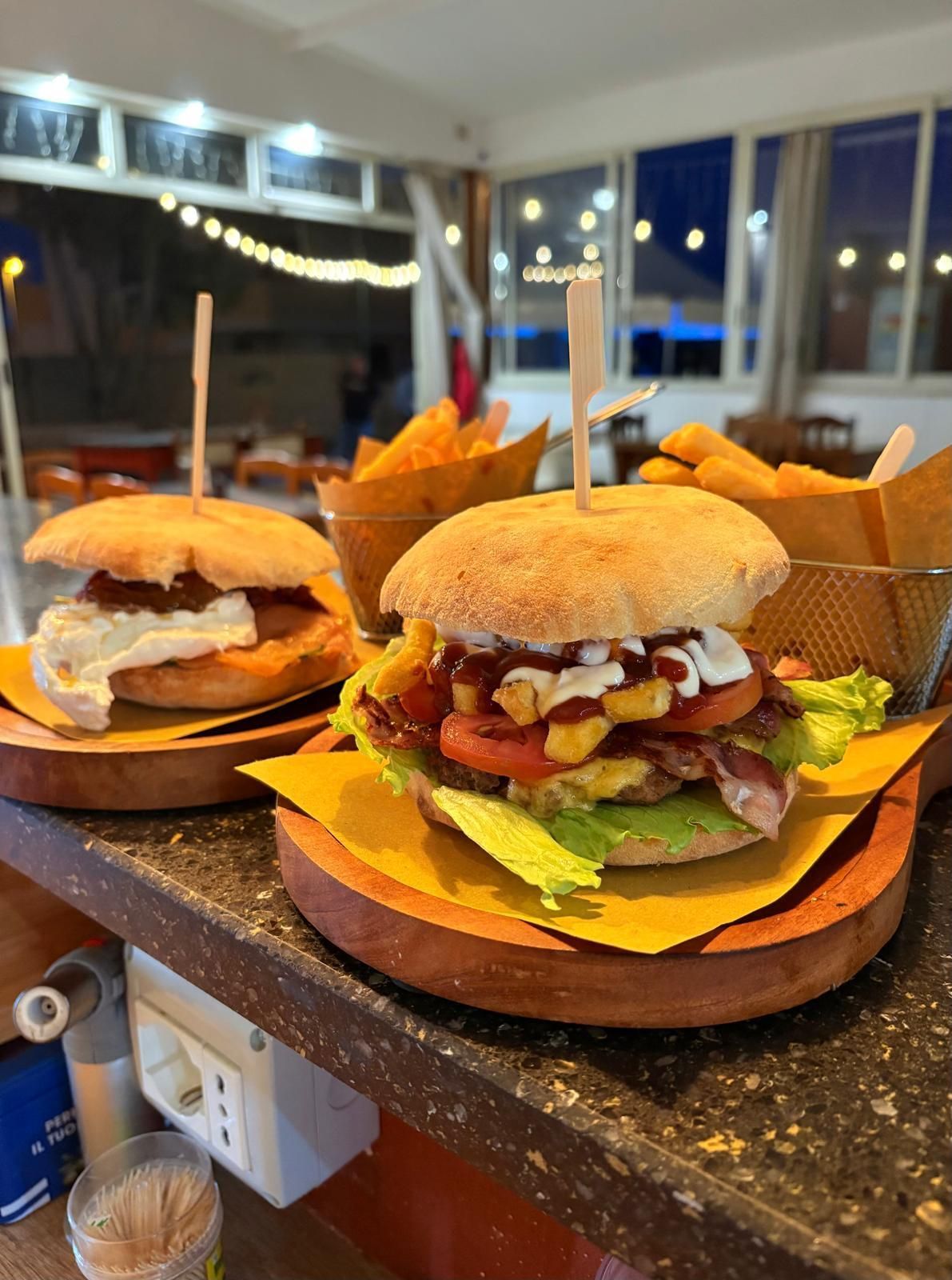 Due hamburger e patatine fritte sono appoggiati su un bancone.