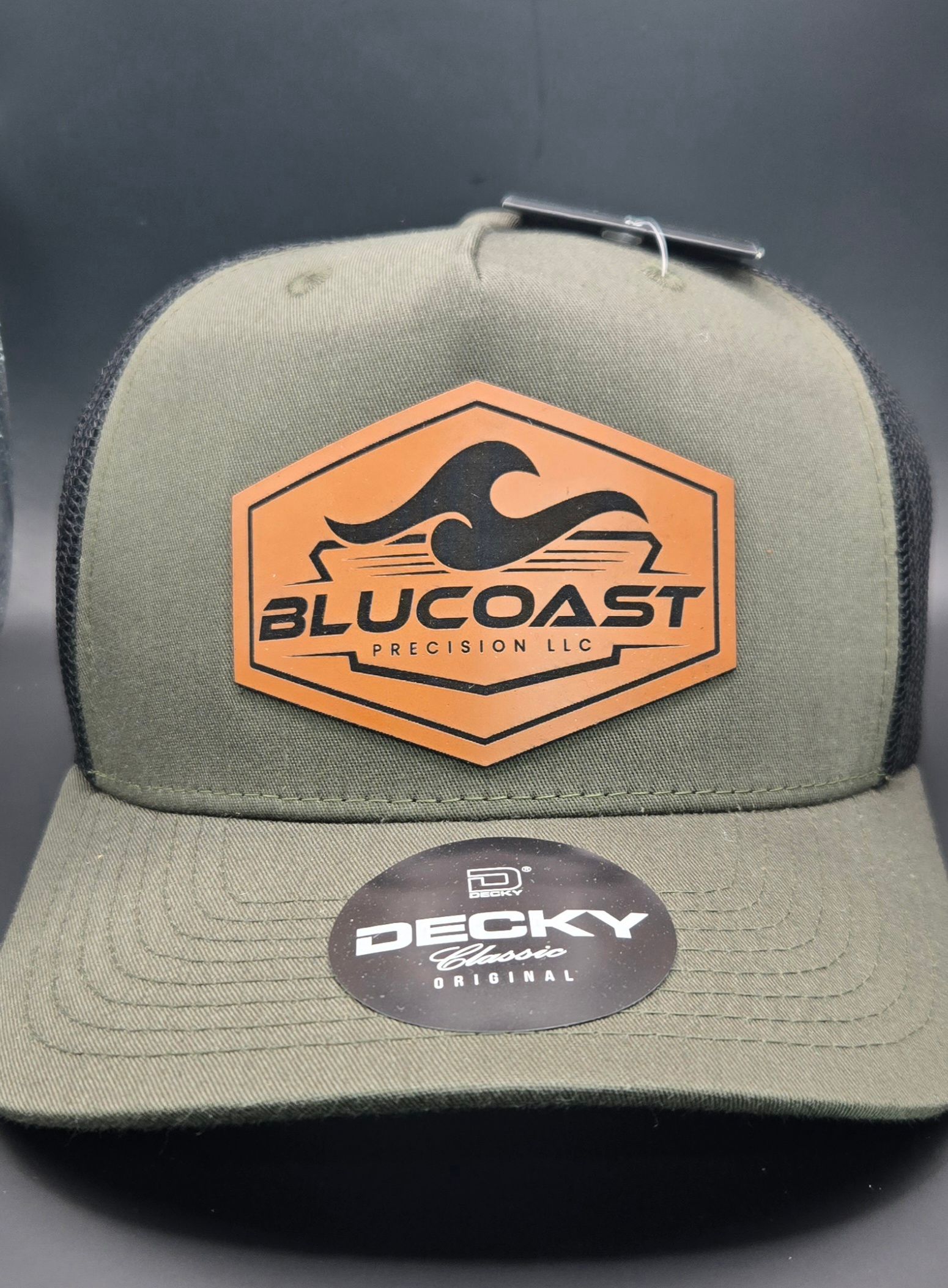 Black baseball cap with brown logo patch. 