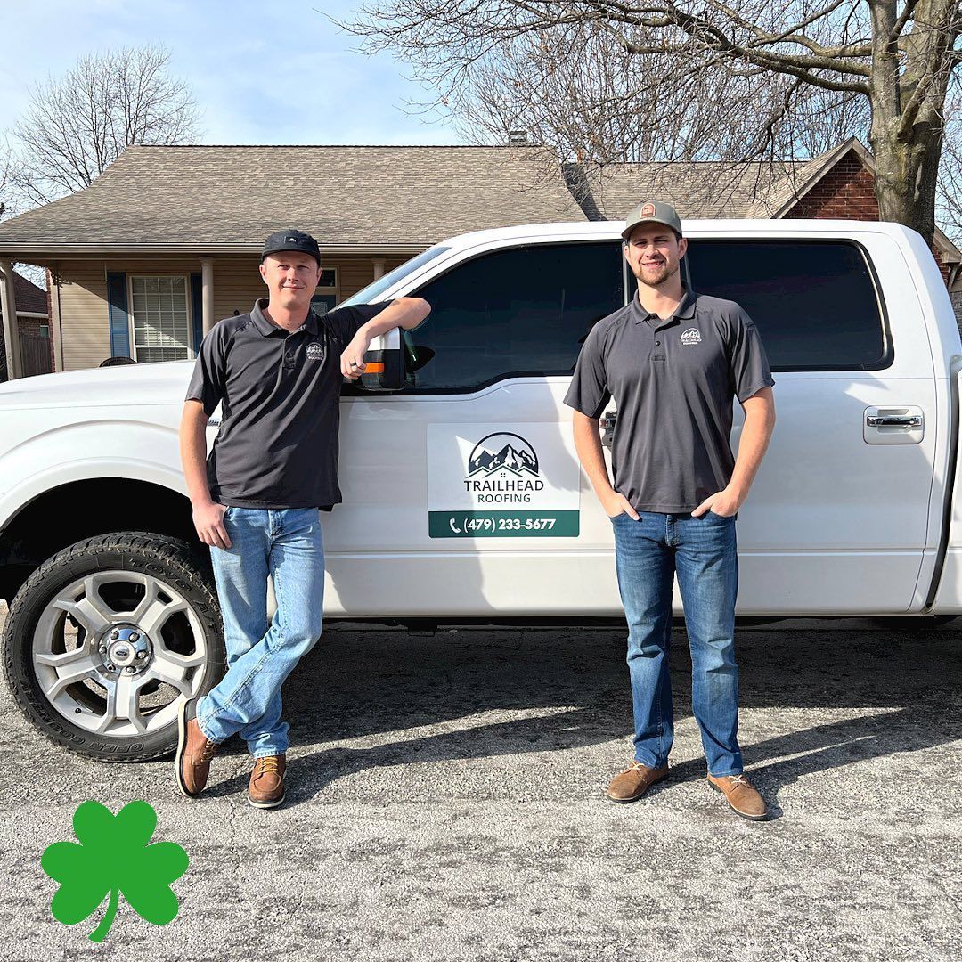 Two men are standing next to a white truck in front of a house.