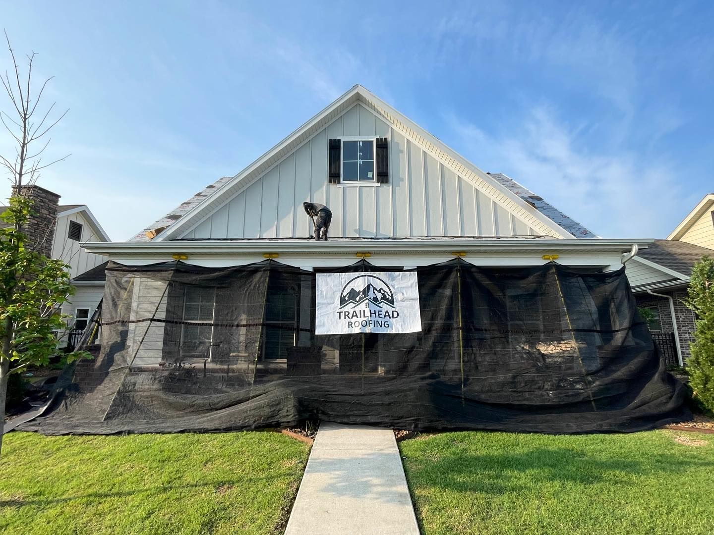 A white house with a black tarp covering the front of it.