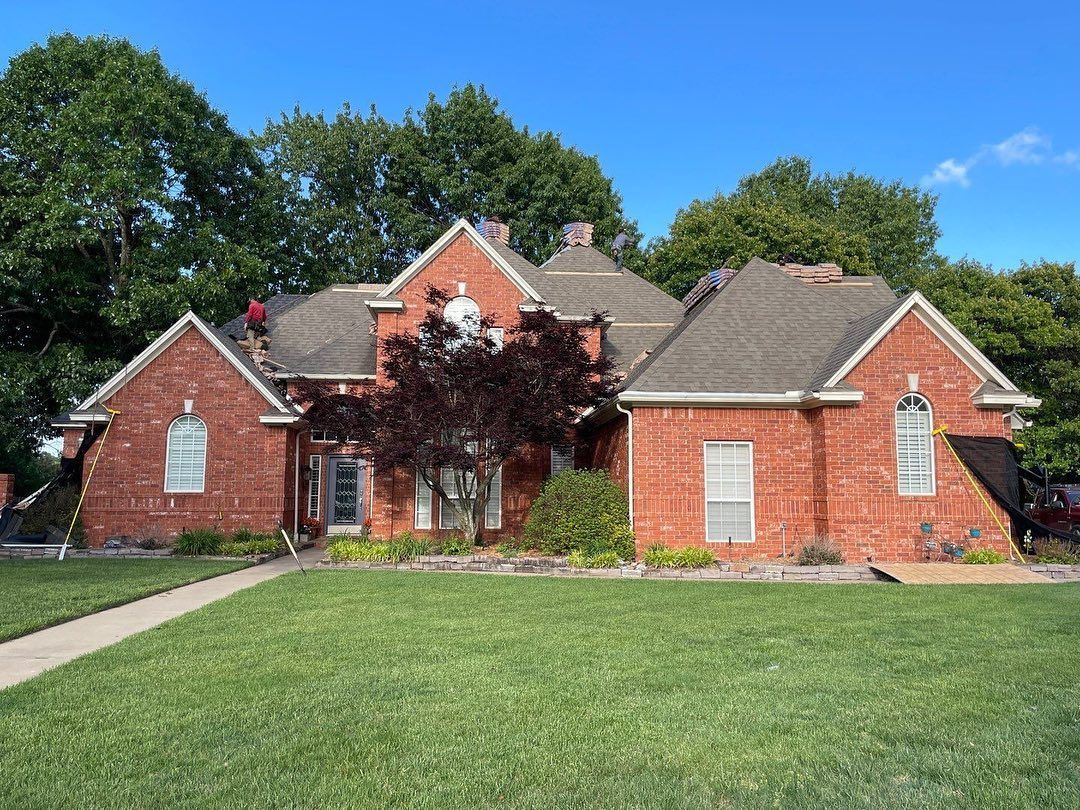 A large brick house with a man on the roof.