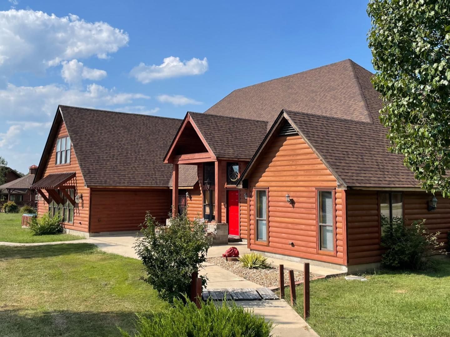 A large wooden house with a red door and a brown roof.