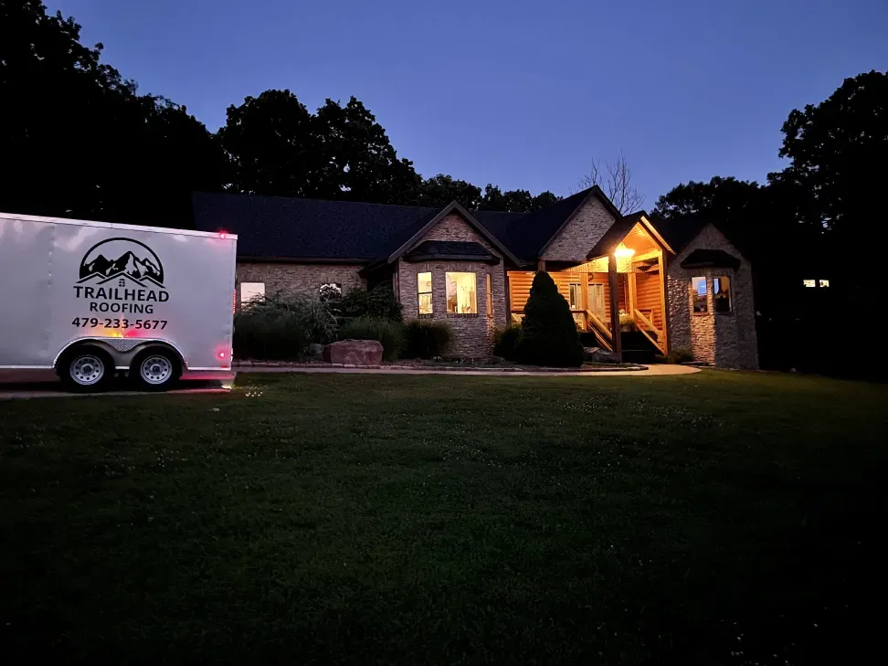 A white trailer is parked in front of a house at night.