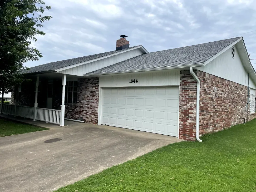 A brick house with a white garage door and a porch.