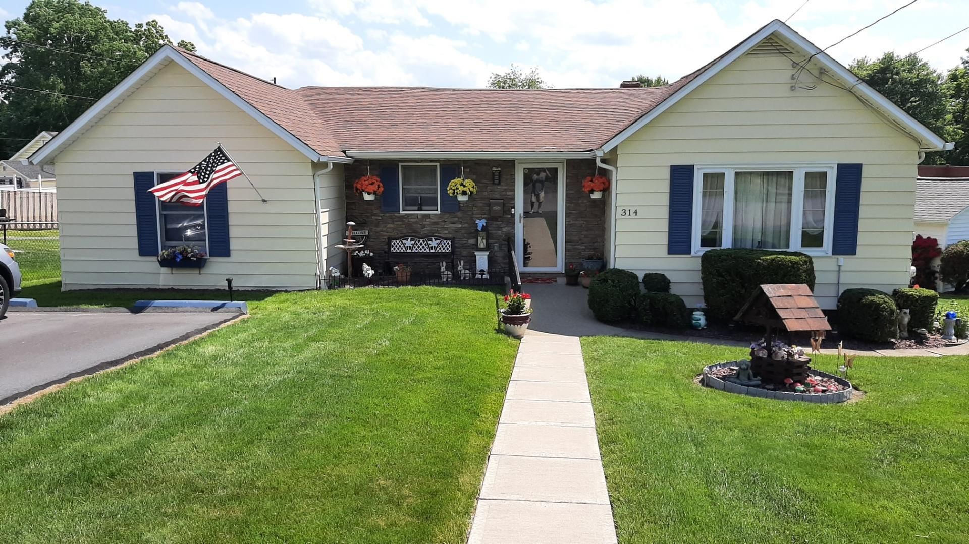 A white house with blue shutters and a walkway leading to it.