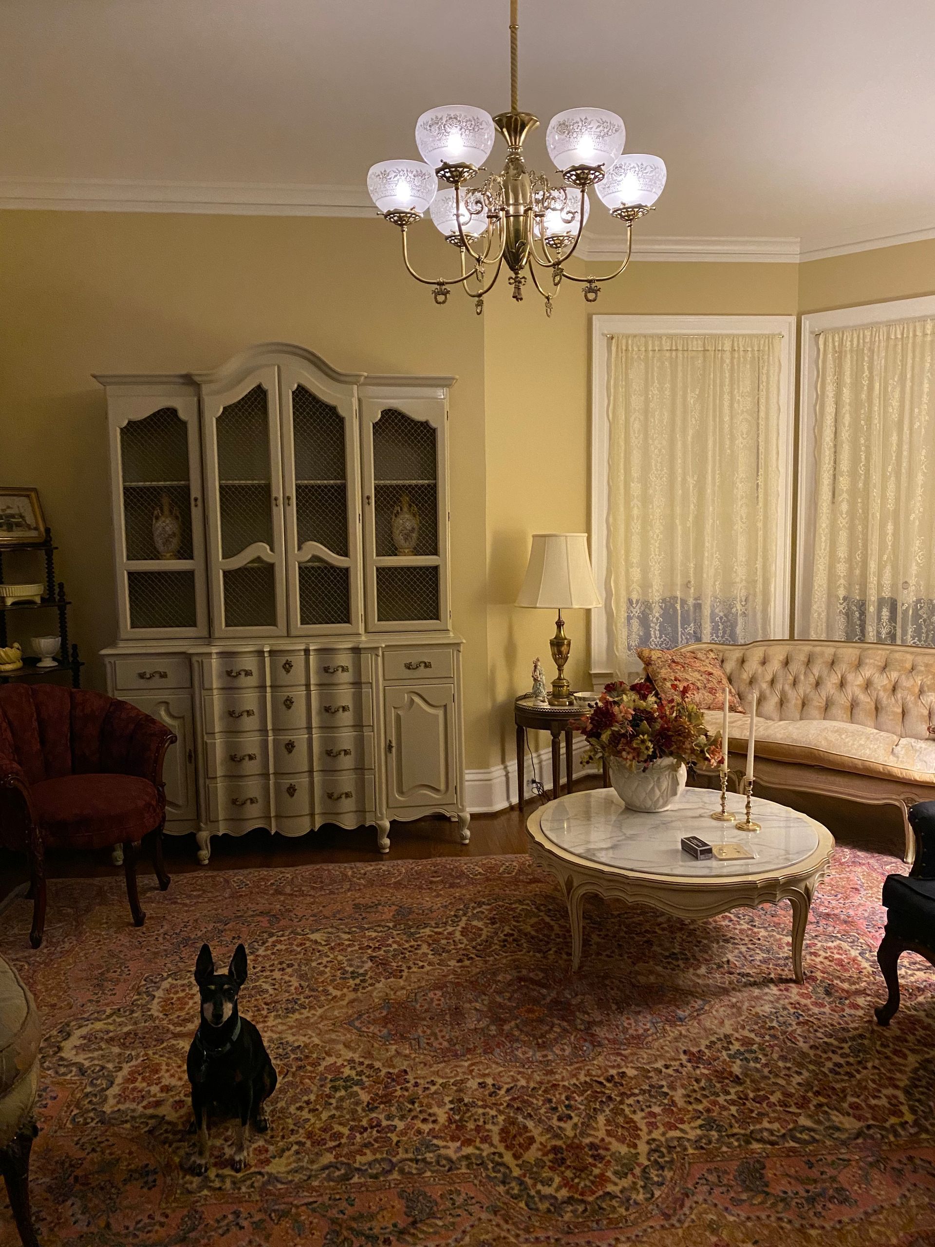 A living room with a couch , chairs , a coffee table and a chandelier.