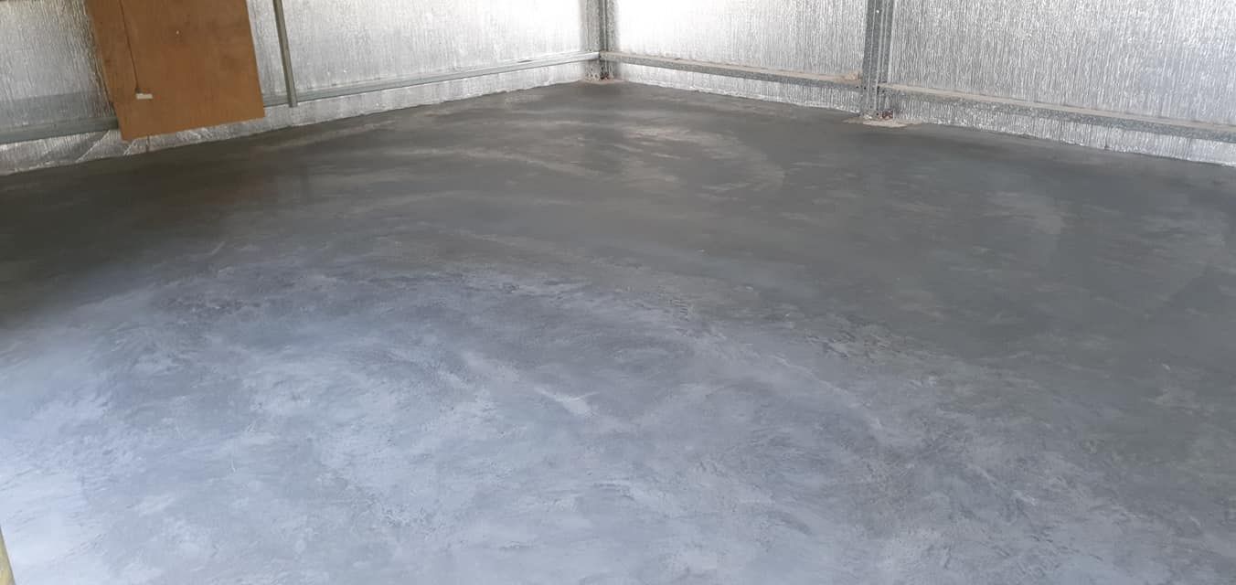 A concrete floor in a garage with a door in the background. — MidCoast Concreting in Mount George, NSW