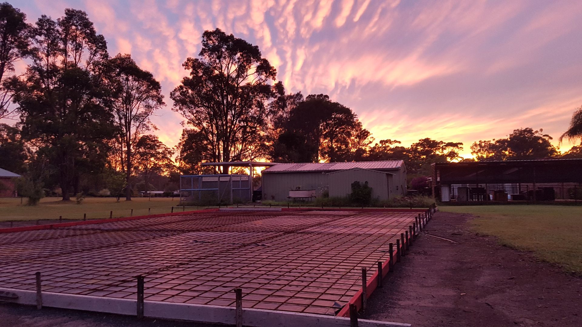 A sunset over a construction site with a house in the background — MidCoast Concreting in Mount George, NSW