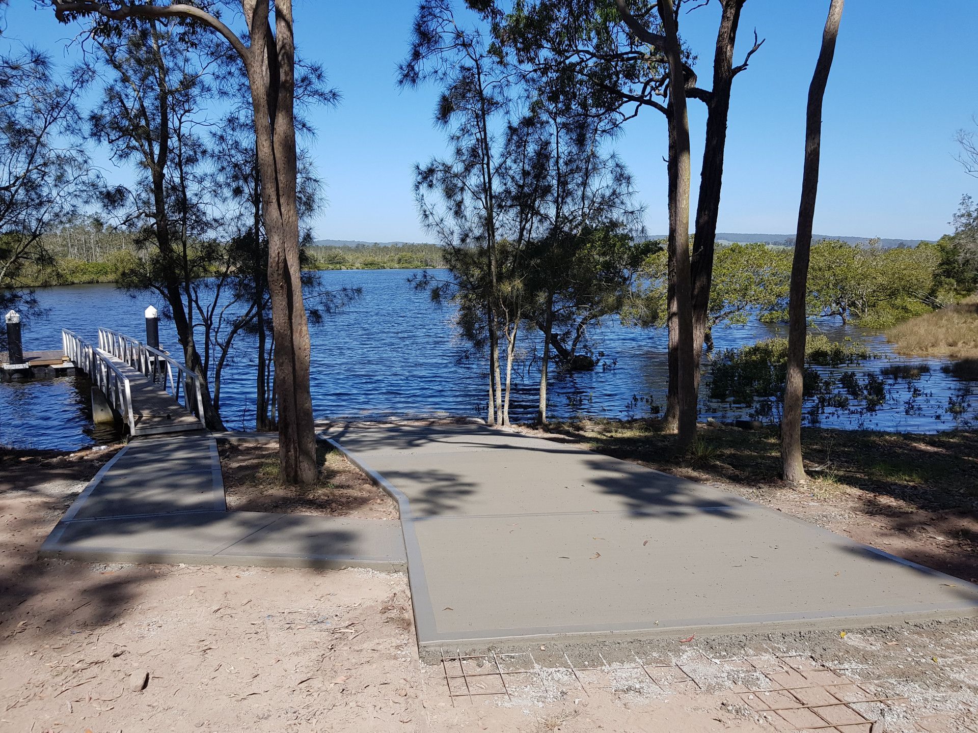 A concrete walkway leading to a dock overlooking a lake — MidCoast Concreting in Mount George, NSW