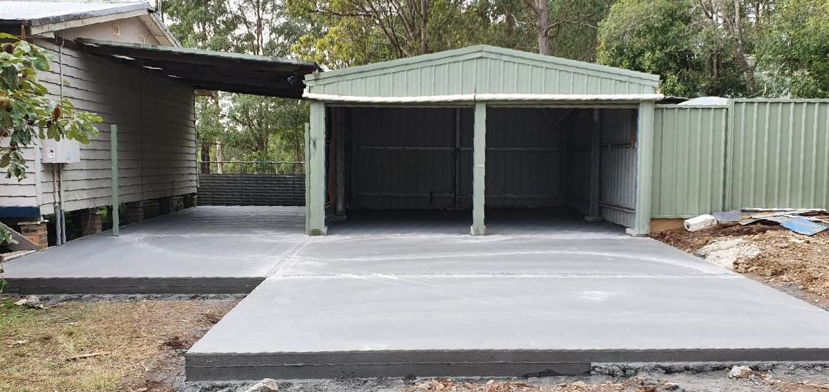 A Concrete Driveway Leading to a Garage With a Green Roof — MidCoast Concreting in Wingham, NSW
