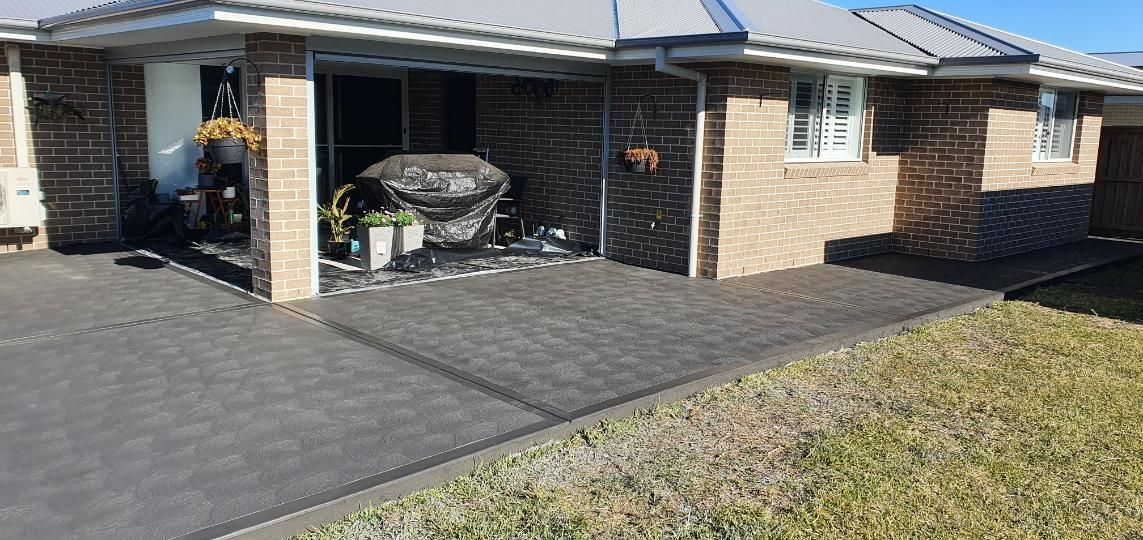 A Brick House With a Concrete Driveway in Front of It — MidCoast Concreting in Lansdowne, NSW