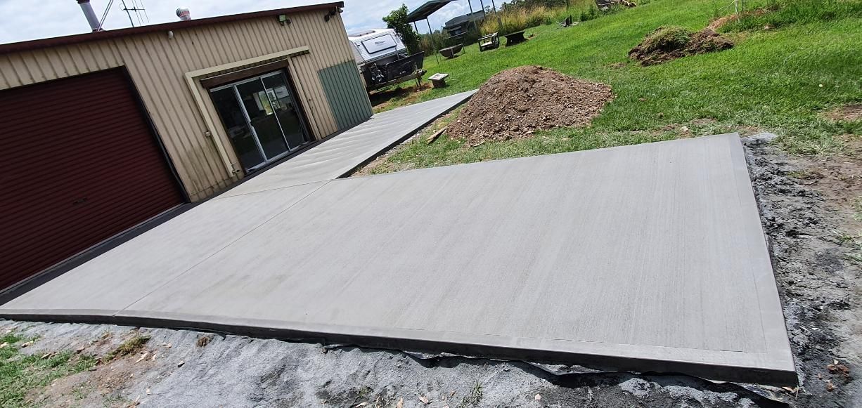 A Concrete Driveway is Being Built in Front of a Garage — MidCoast Concreting in Harrington, NSW