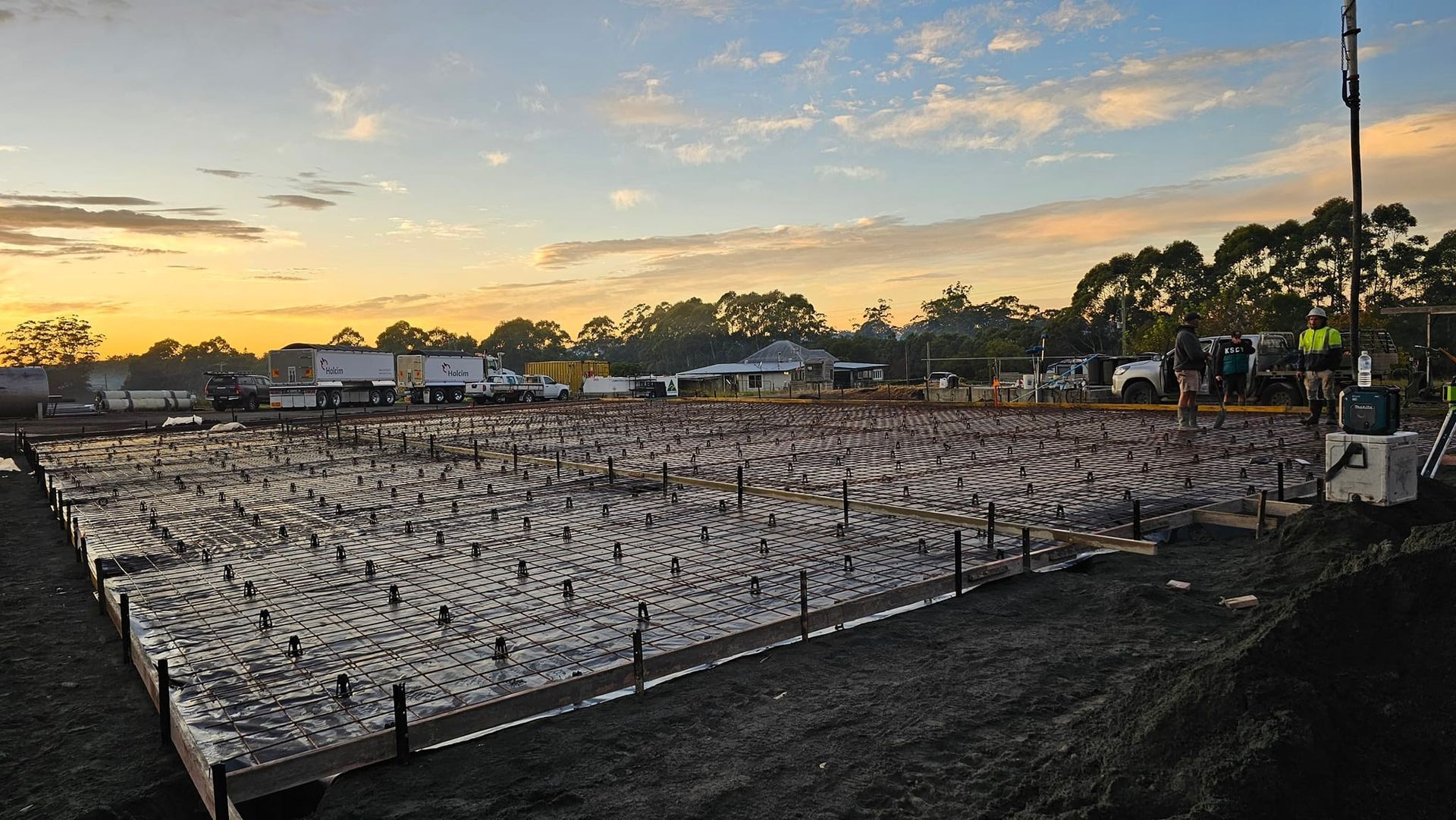 A Trowel is Laying on a Concrete Surface Next to a Wheelbarrow — MidCoast Concreting in Mount George, NSW