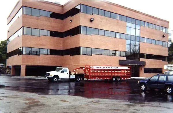 A white truck is parked in front of a large brick building.