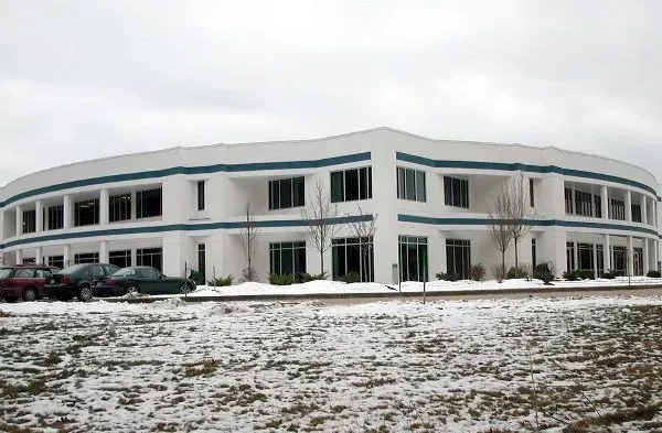 A large white building with blue trim is surrounded by snow.