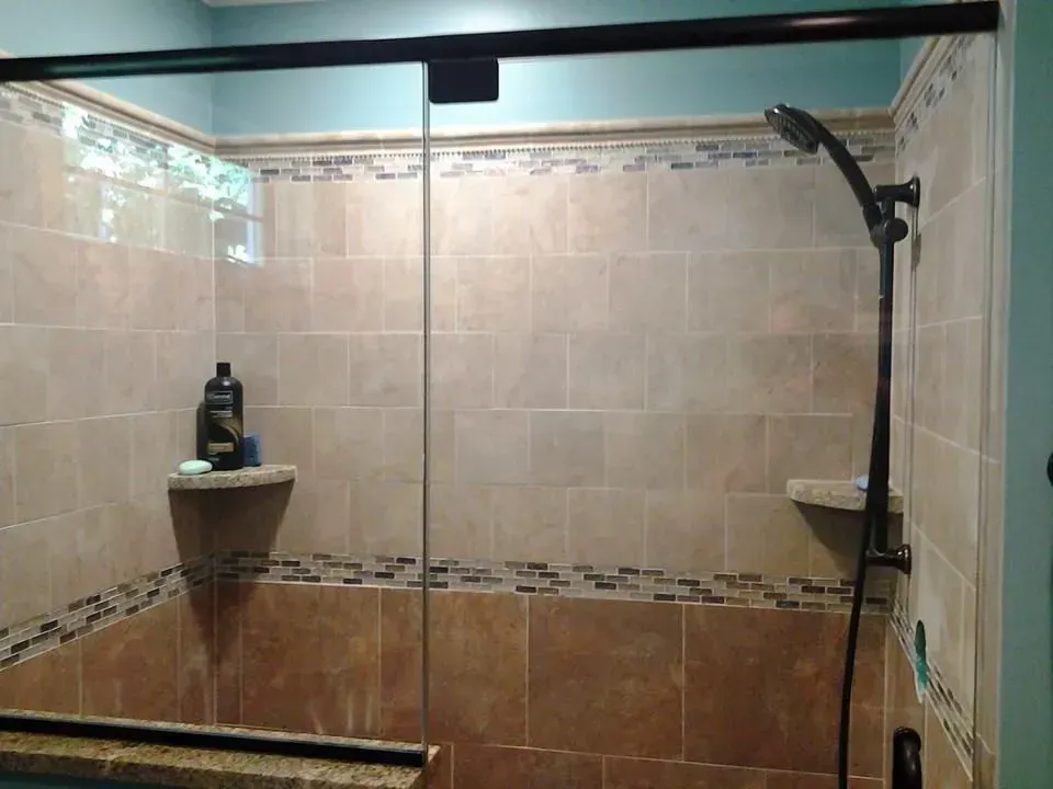 A shower with a sliding glass door and a shower head.