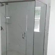 A bathroom with a glass shower door and a window.