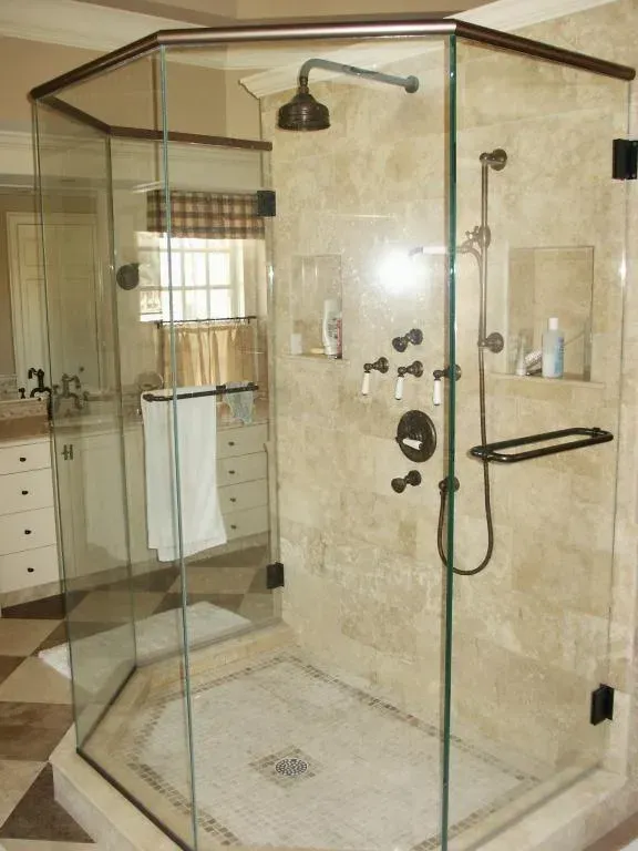 A bathroom with a walk in shower with a glass door.