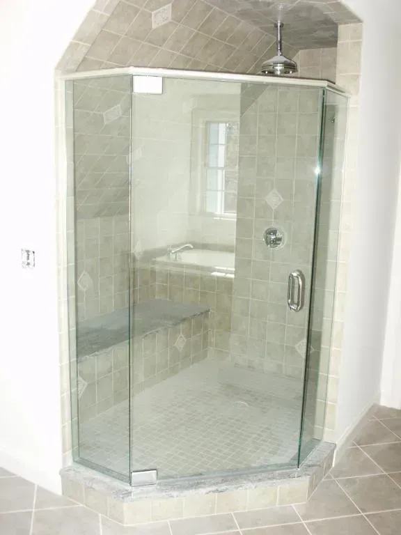 A bathroom with a glass shower door and a bathtub.