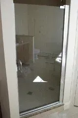 A bathroom with a glass shower door and a sink.