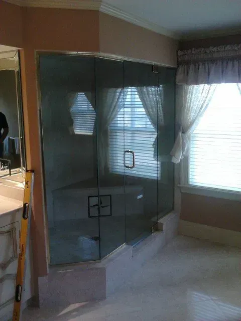 A bathroom with a glass shower door and a window.