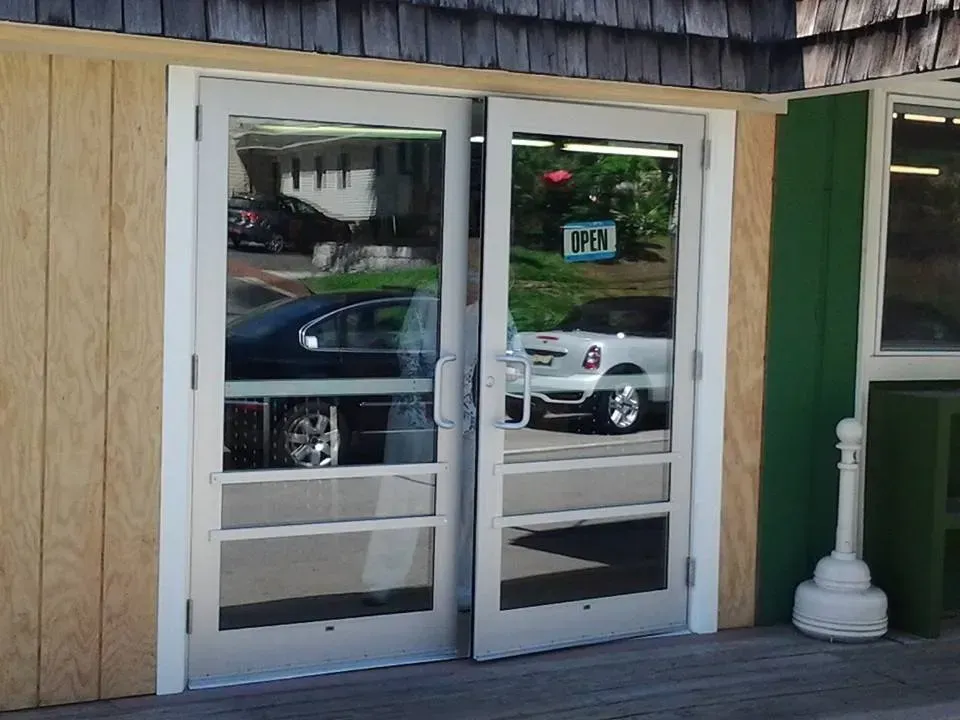 A car is reflected in the glass doors of a building.