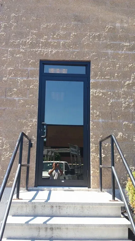 A door with stairs leading up to it and a reflection of a person in the door.