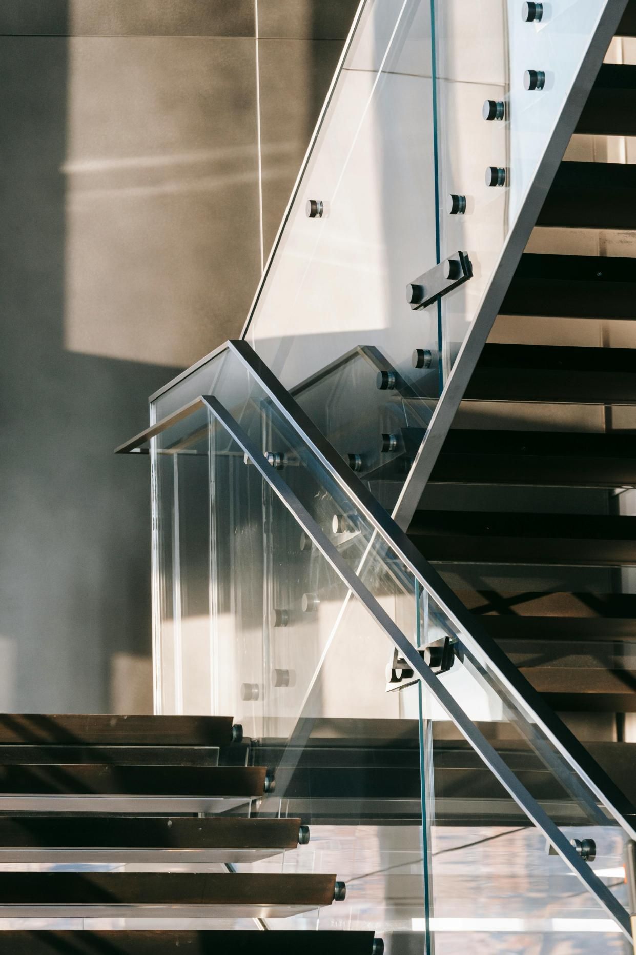A close up of a modern staircase with a glass railing.