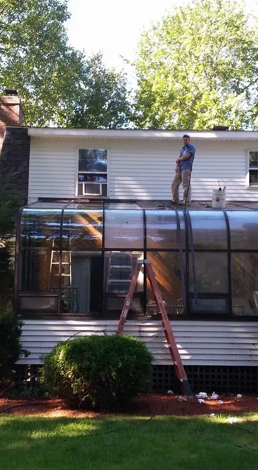 A man is standing on the roof of a house.