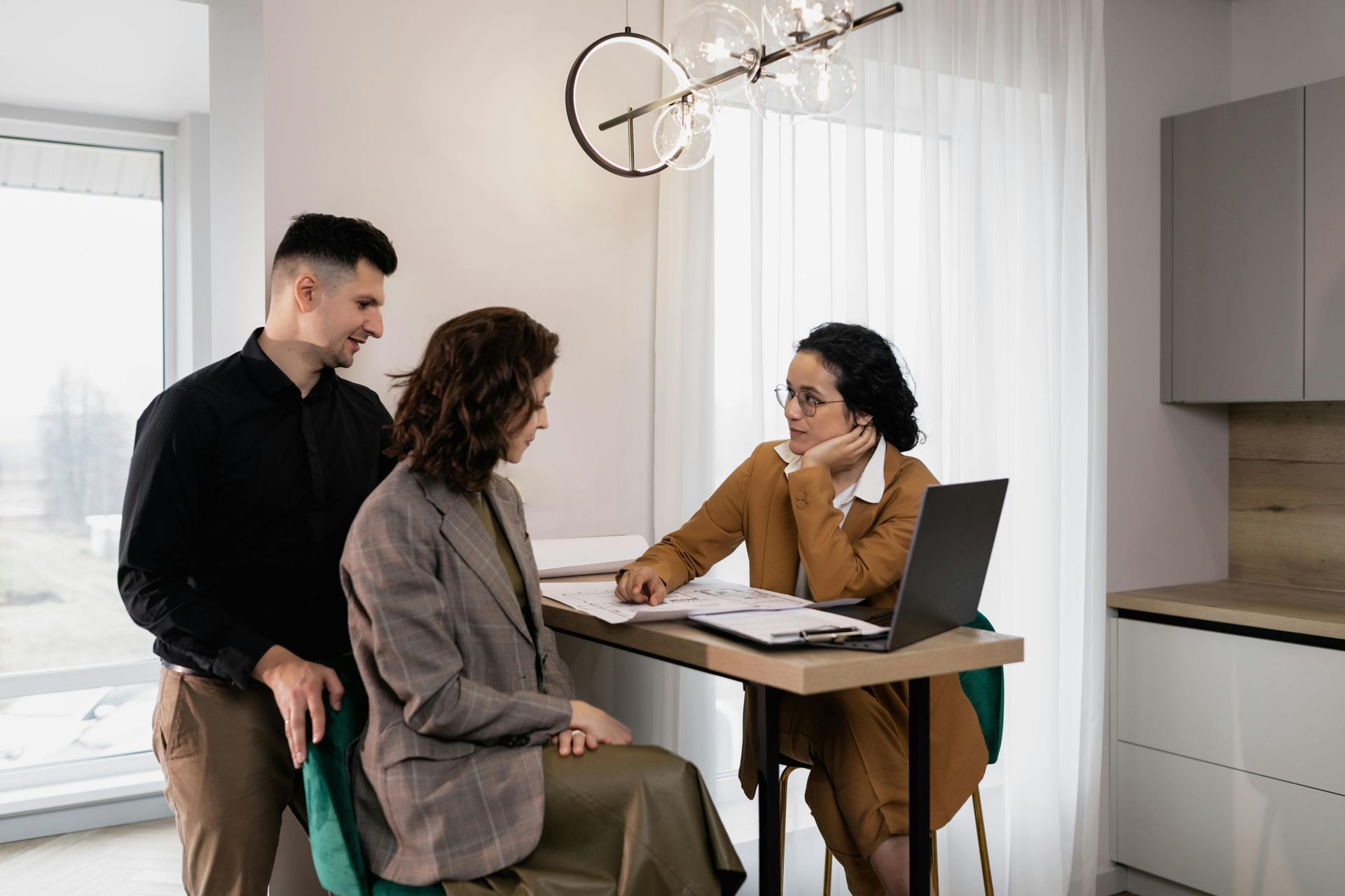 People in business attire at a wooden table reviewing financial data; using calculator, tablet and pens.