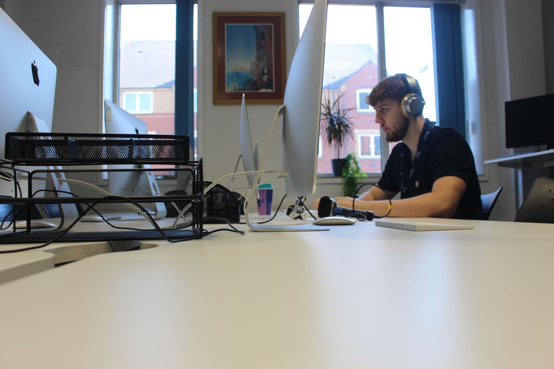 Man wearing headphones at a desk, using a computer in an office setting.