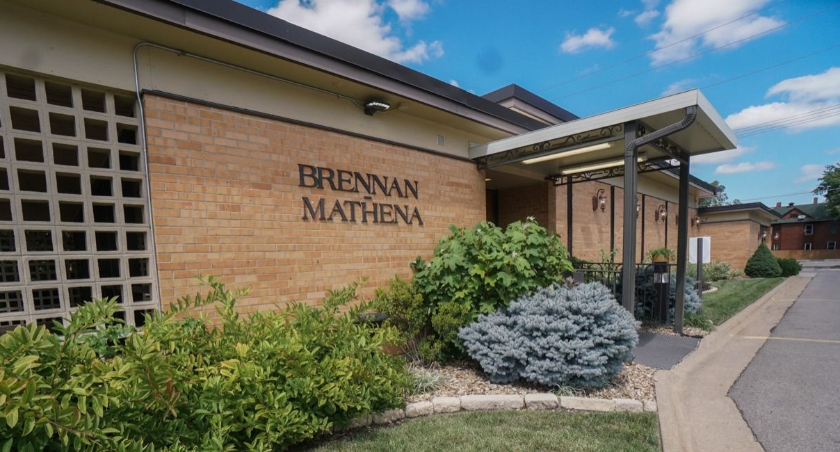 A man in a suit is sitting at a coffin at a funeral.