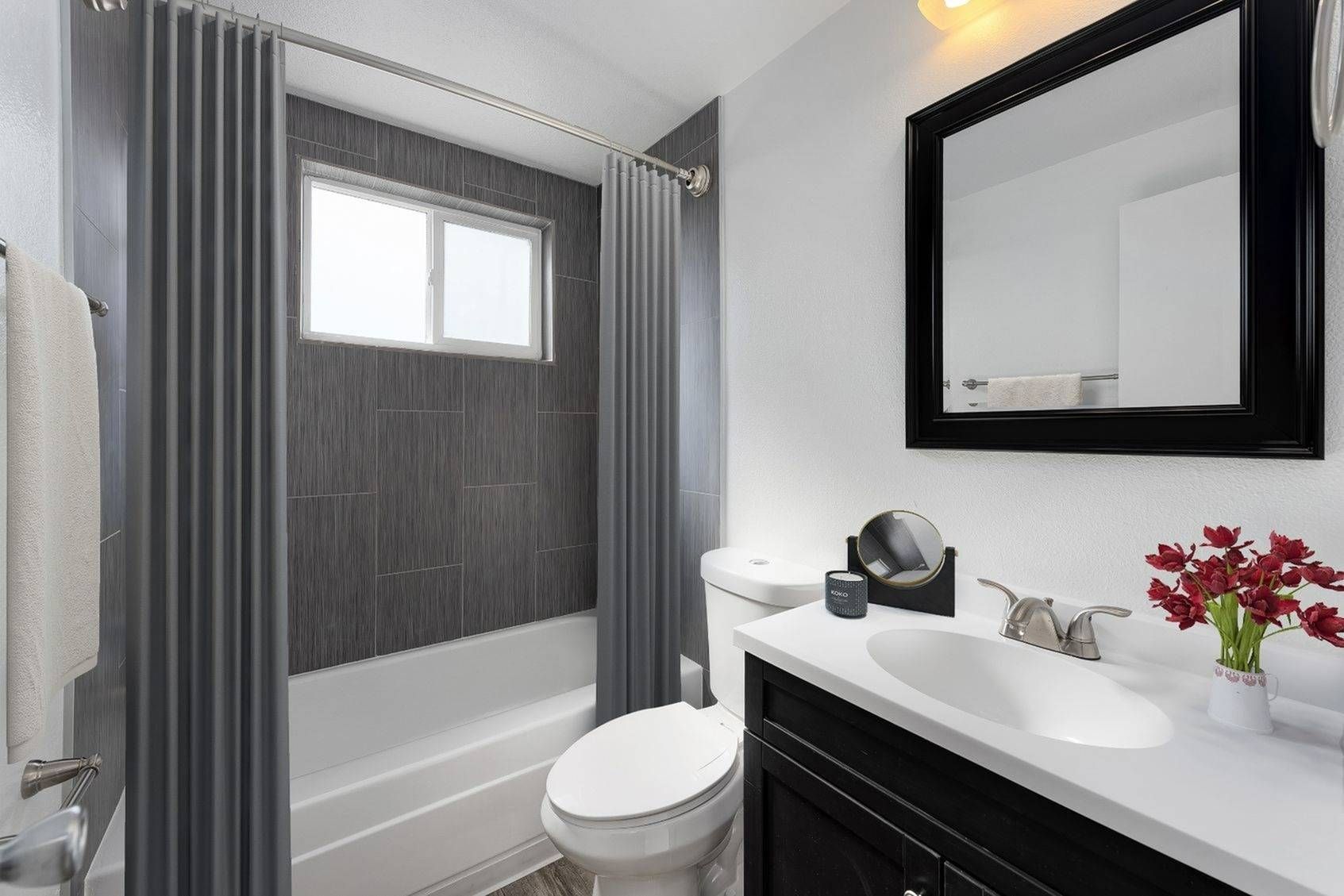 Modern apartment bathroom with shower/bath, toilet, sink, and mirror at Southglenn Place.