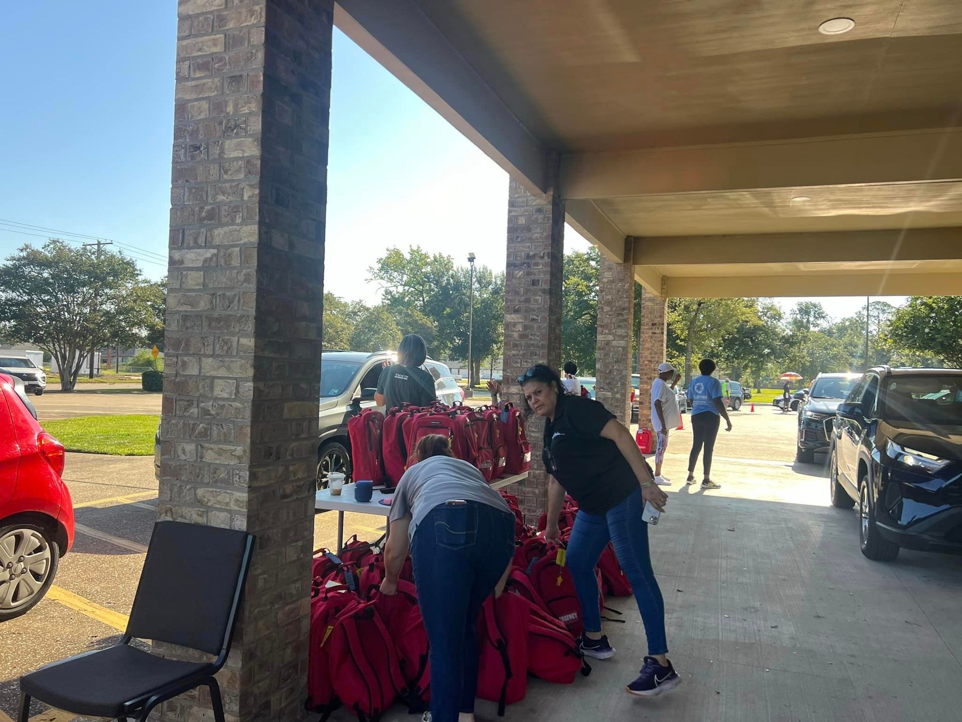 A group of people are standing under a canopy in a parking lot.