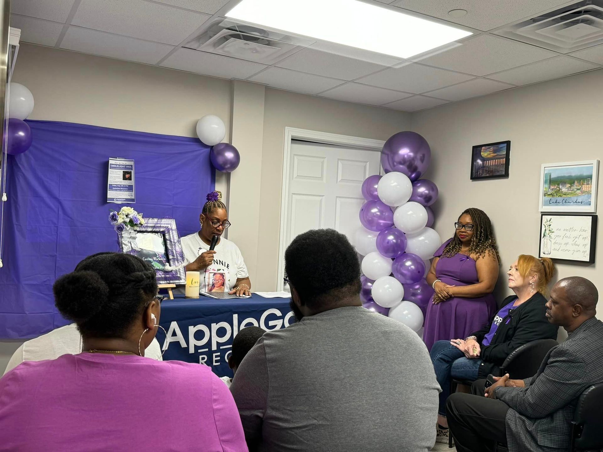 A womman is giving a presentation to a group of people in a room.