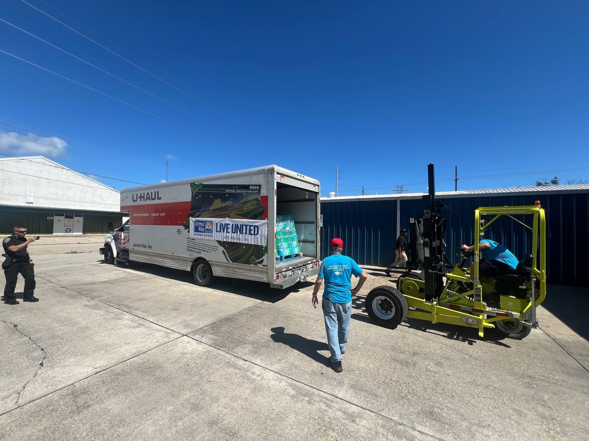 A man is walking towards a truck with a forklift attached to it.