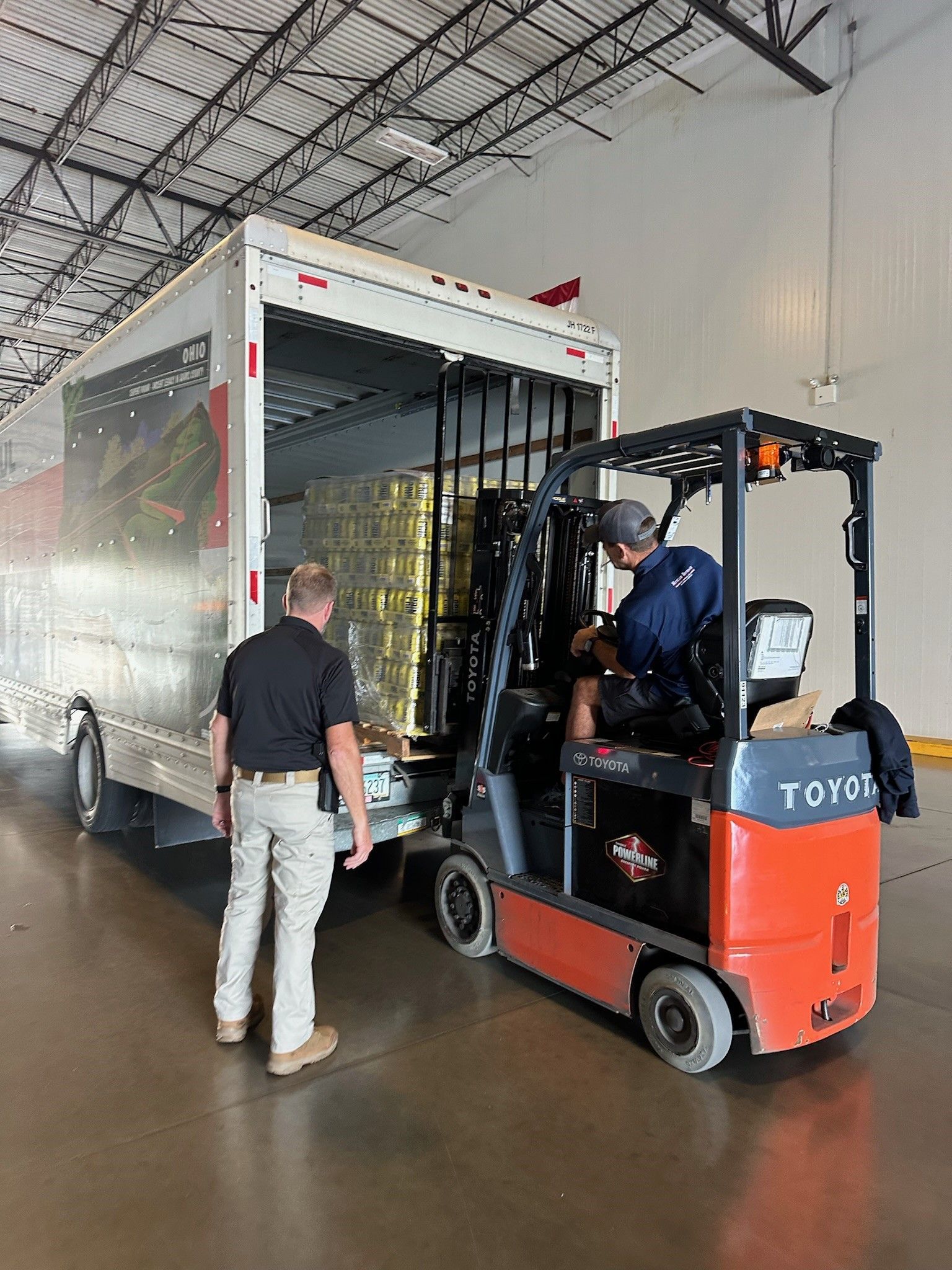 A man is standing next to a forklift in a warehouse.