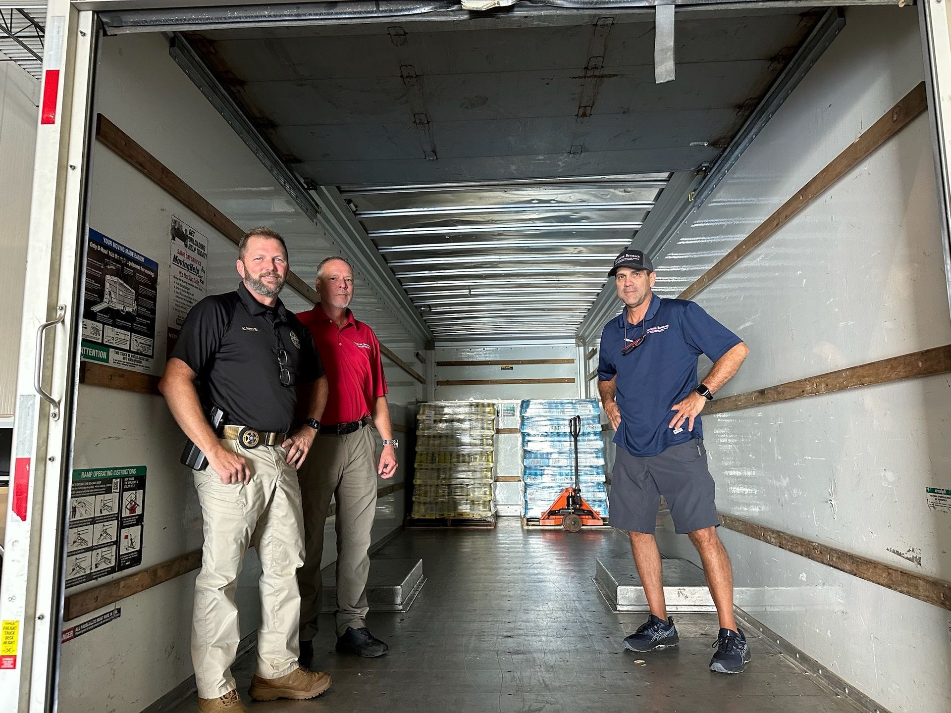 Three men are standing in the back of a truck.
