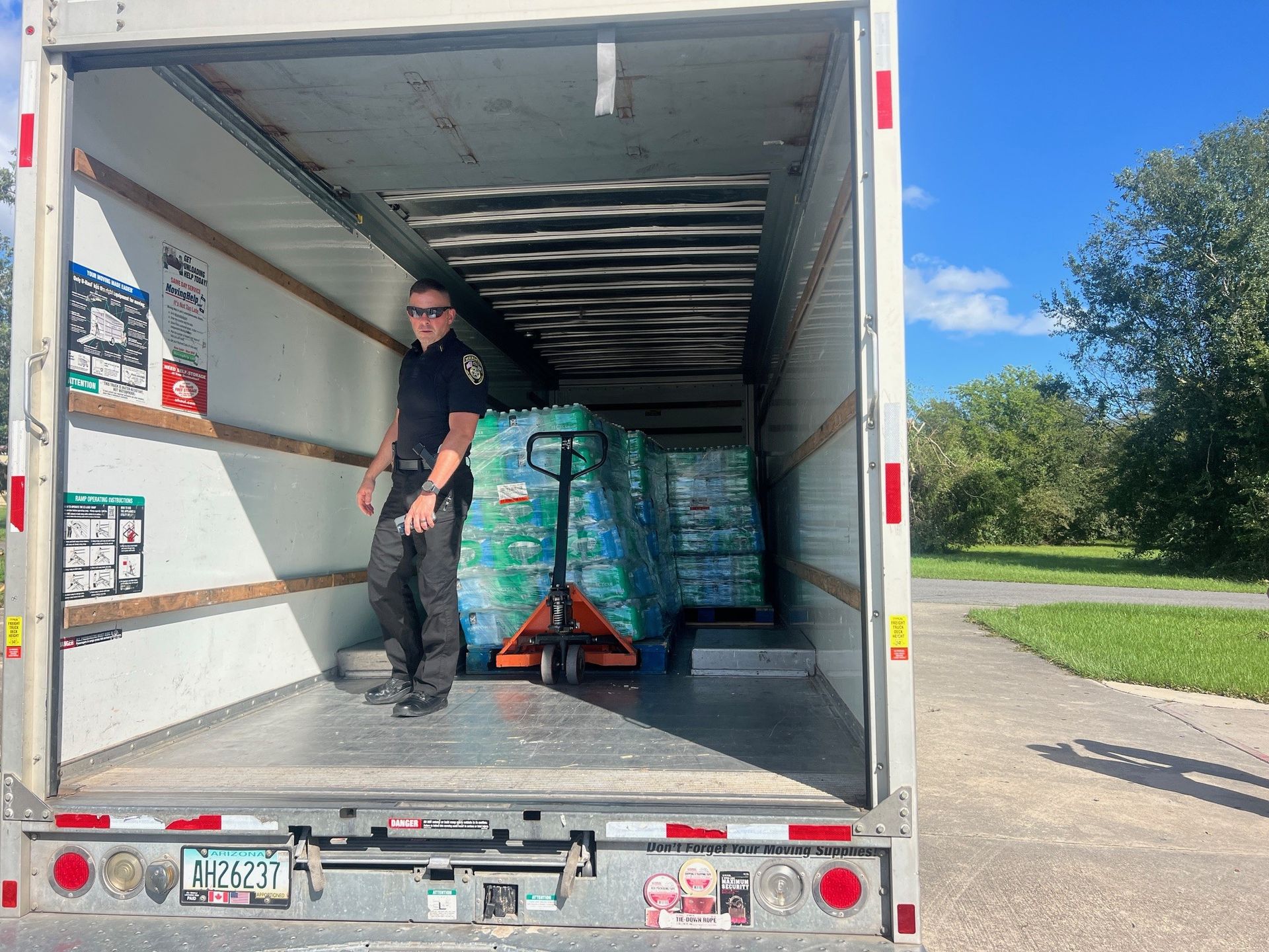 A man is standing in the back of a truck filled with water bottles.