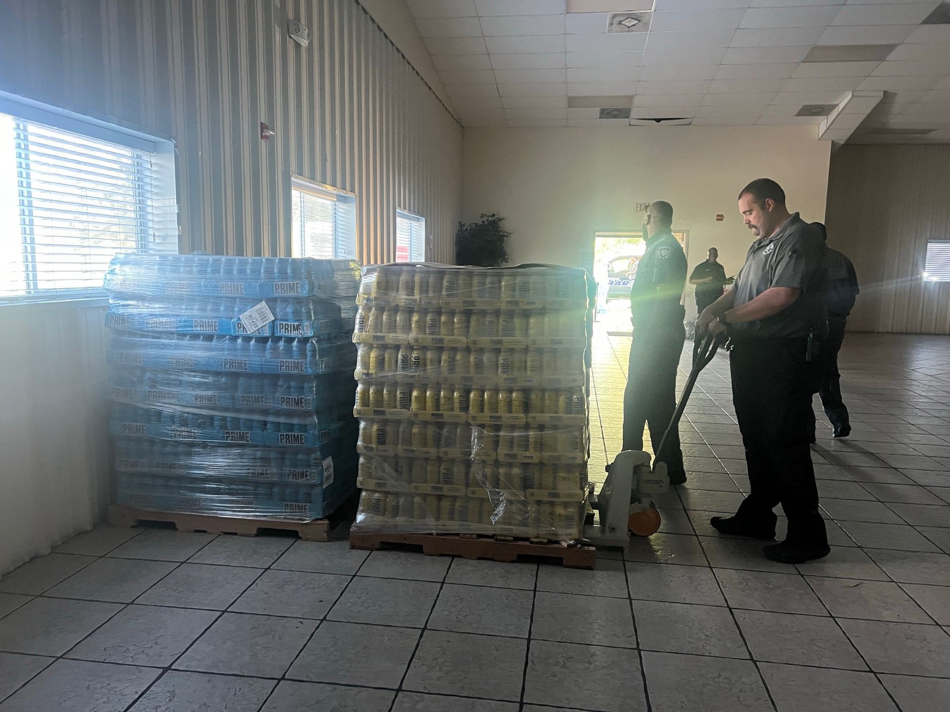 A man is standing next to a pallet of water bottles