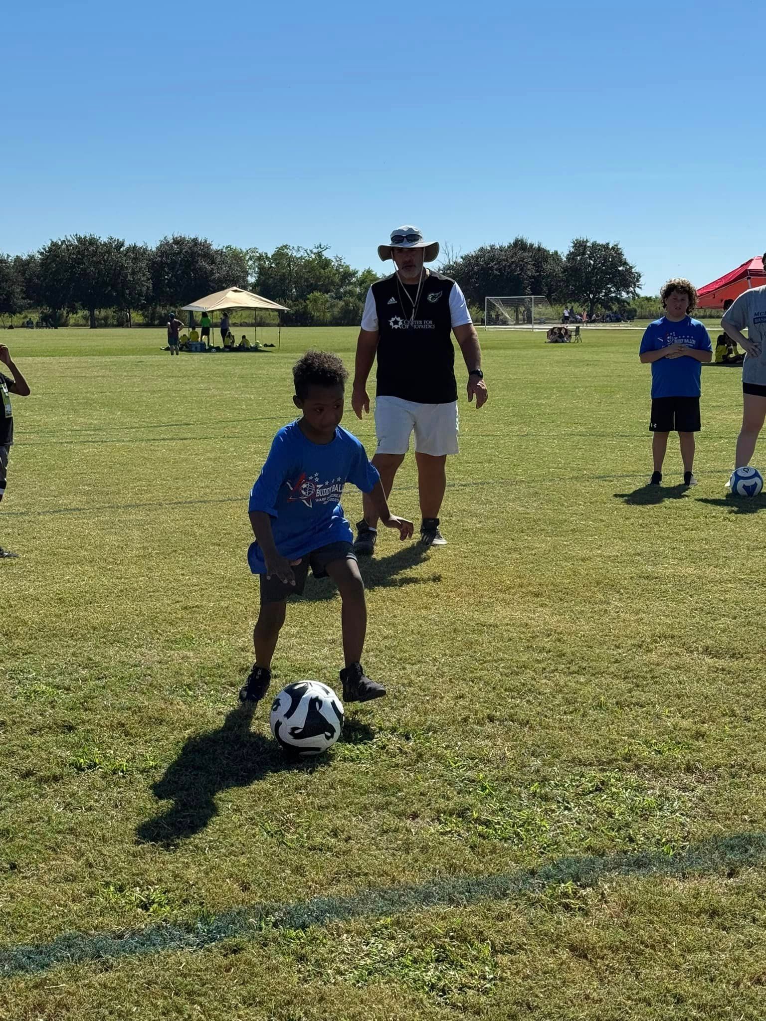 A boy in a blue shirt is kicking a soccer ball