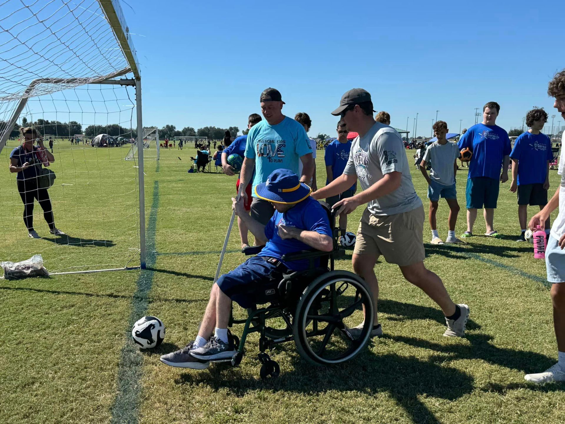 A man in a wheelchair is playing soccer with a group of people.