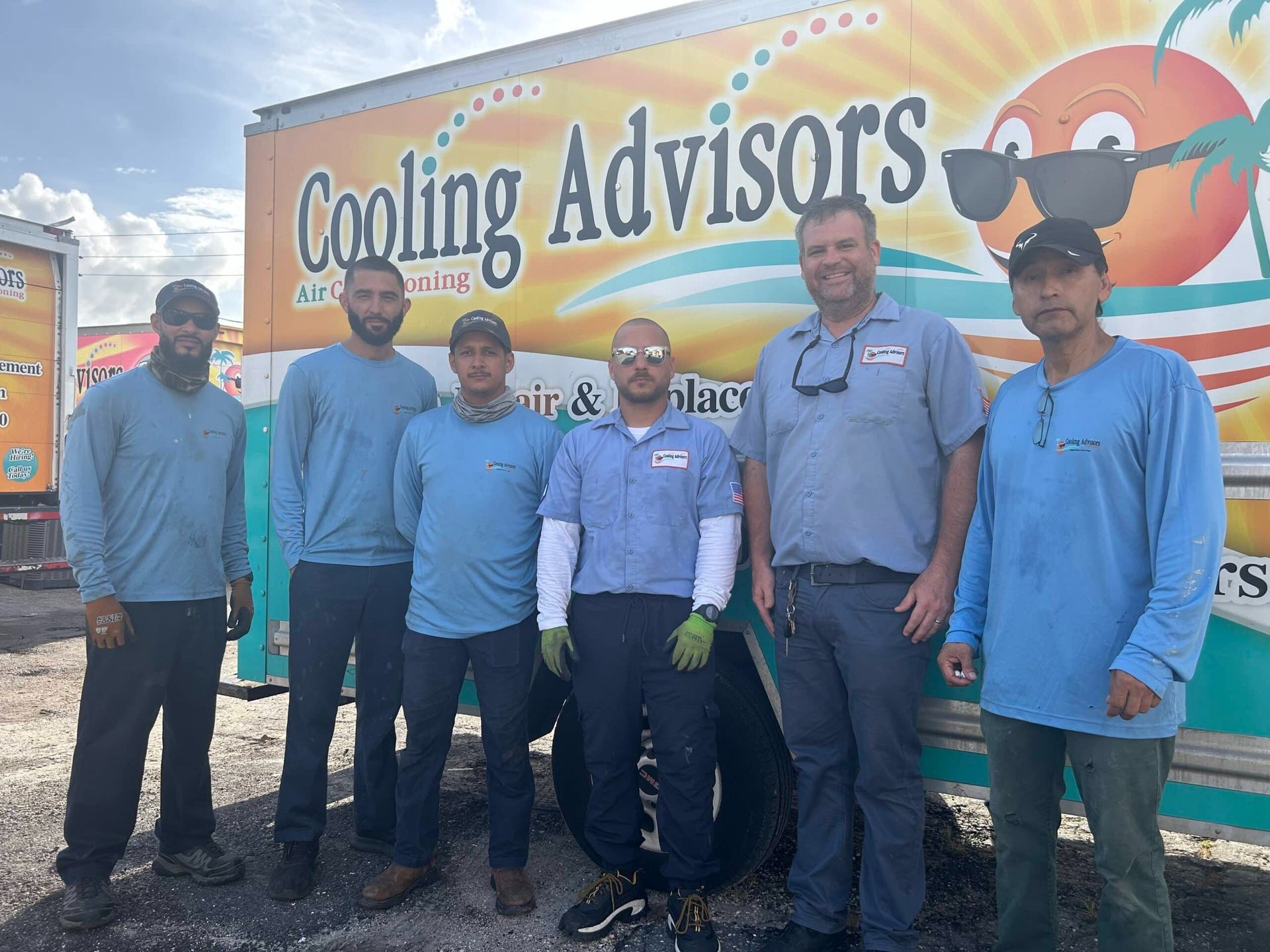 Six people in blue shirts stand in front of a truck with the words 
