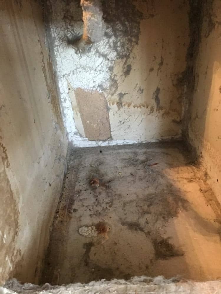 Inside of an empty, deteriorating concrete box with stained walls and floor.