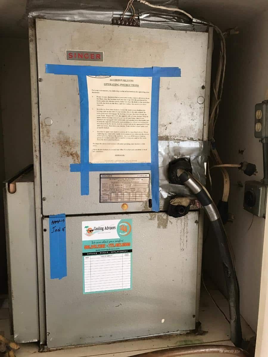 Old Singer HVAC unit in a utility space, with taped service notices.