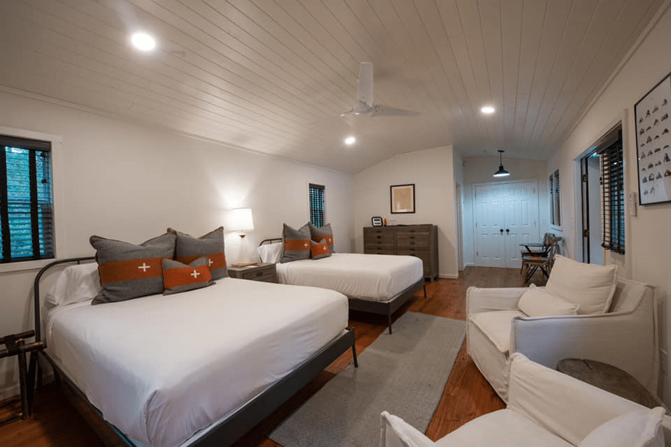 A bedroom with two beds , a chair , and a ceiling fan.