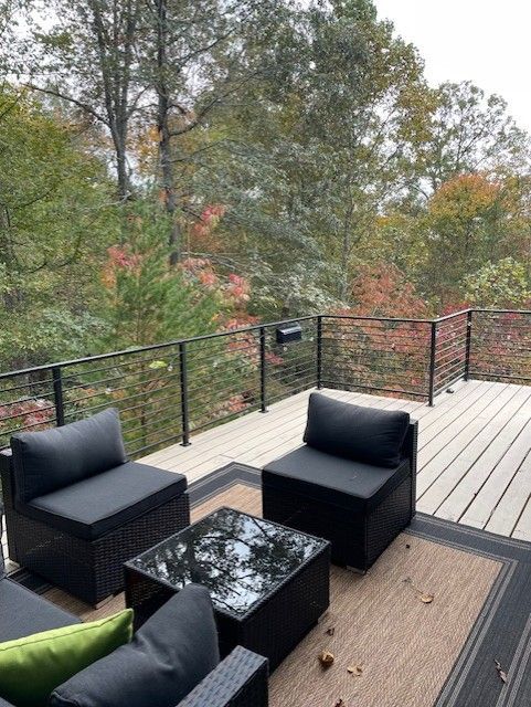 A deck with chairs and a table with trees in the background